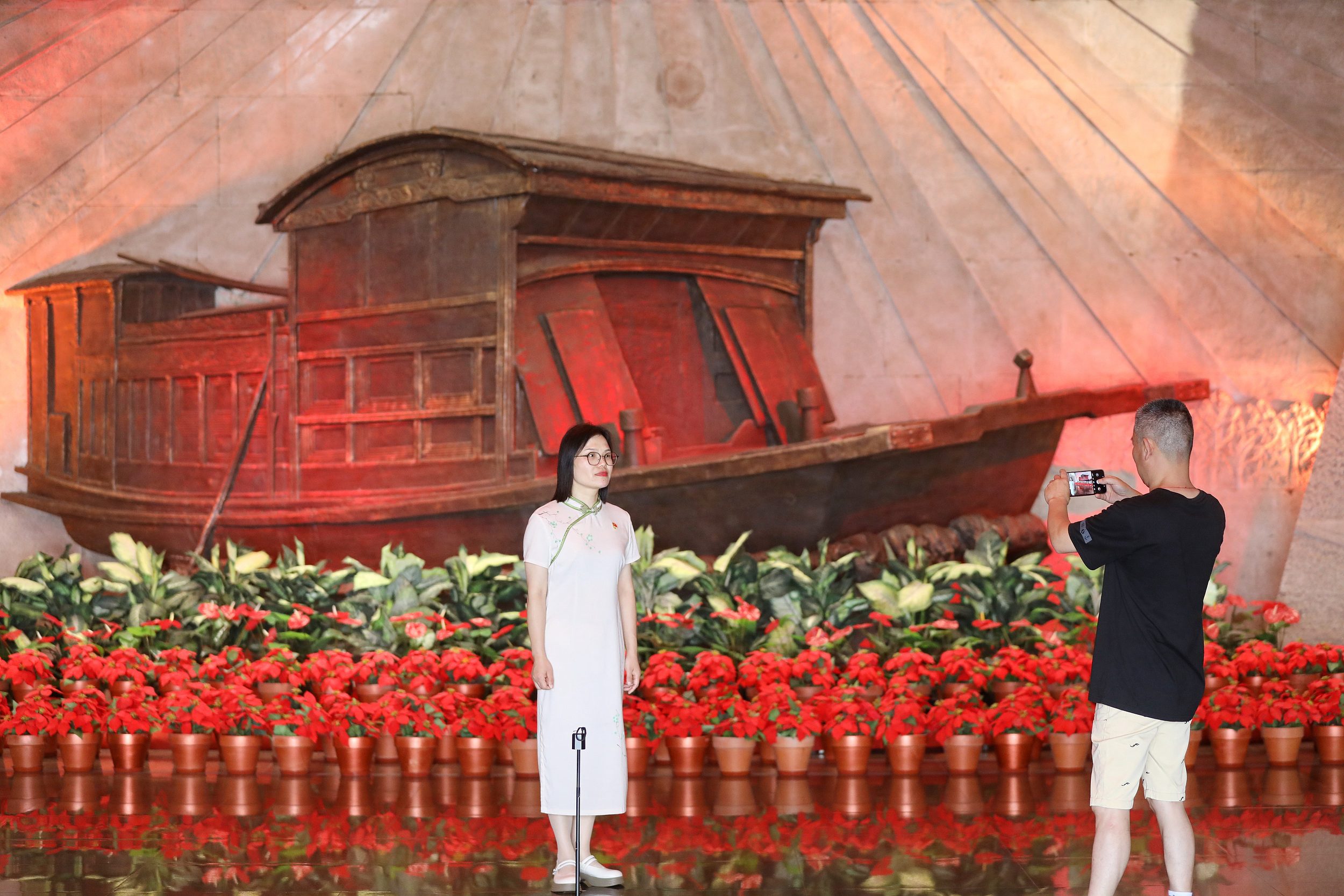 2025年6月24日，浙江嘉興，游客在南湖革命紀(jì)念館與紅船雕塑合影。（圖片來(lái)源：視覺(jué)中國(guó)）